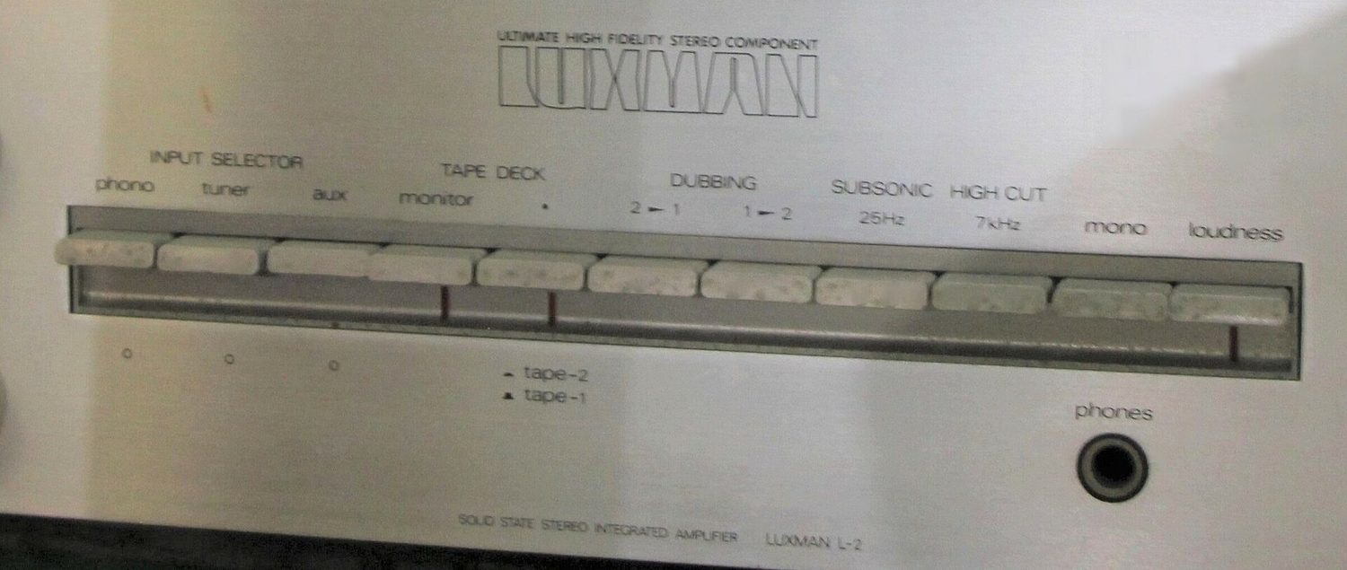 Input selector and tape monitor switches belwo logo on Luxman audio amplifier L-2 (cropped)