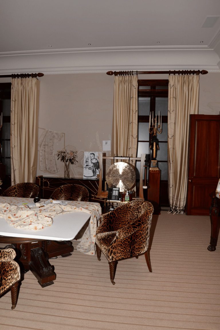 EFTA00000941 - Cozy living room with leopard-print chairs a patterned tablecloth and elegant curtains framing a window