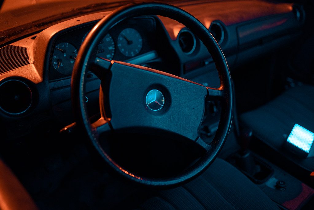 Classic luxury car interior showcases elegant steering wheel and dashboard details under moody lighting at night