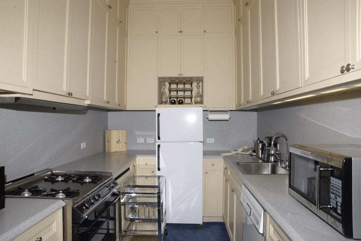 EFTA00000104 - Modern kitchen with cream cabinets a white refrigerator stainless steel appliances and gray countertops