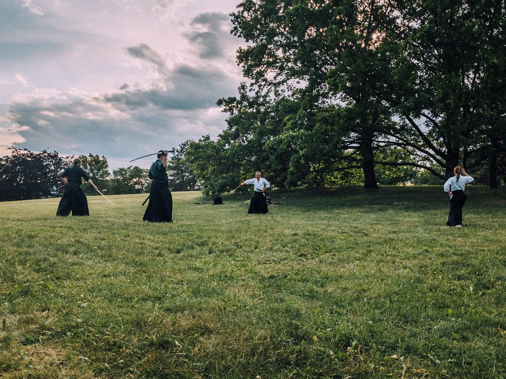 Martial arts instructor and his students practicing with katana swords in the field